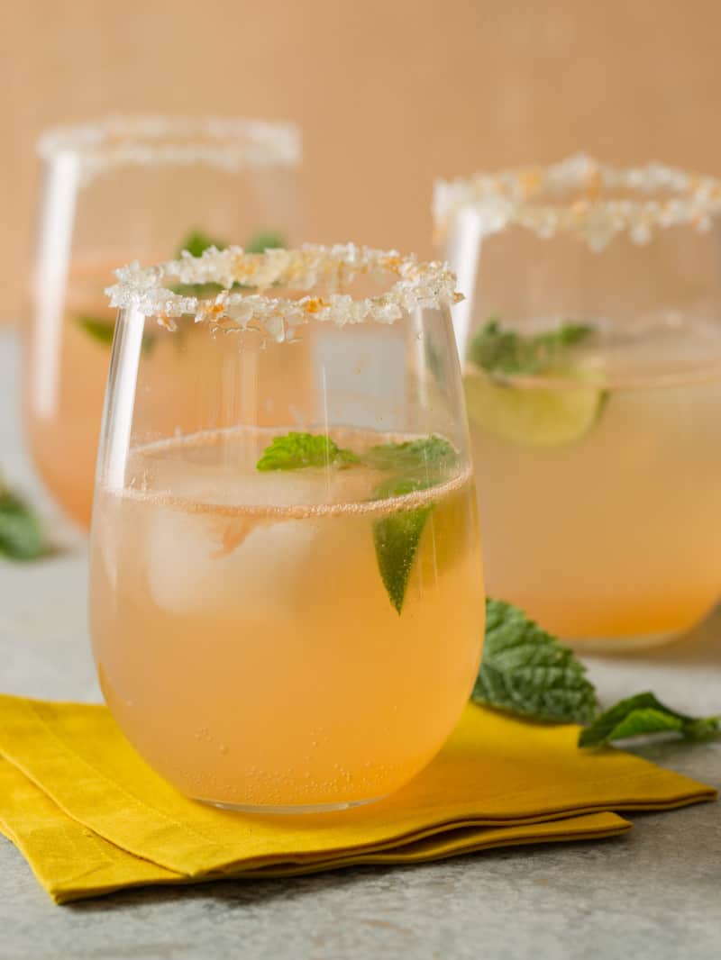 A close up of glasses of paloma with honey salt rim and fresh mint leaves.