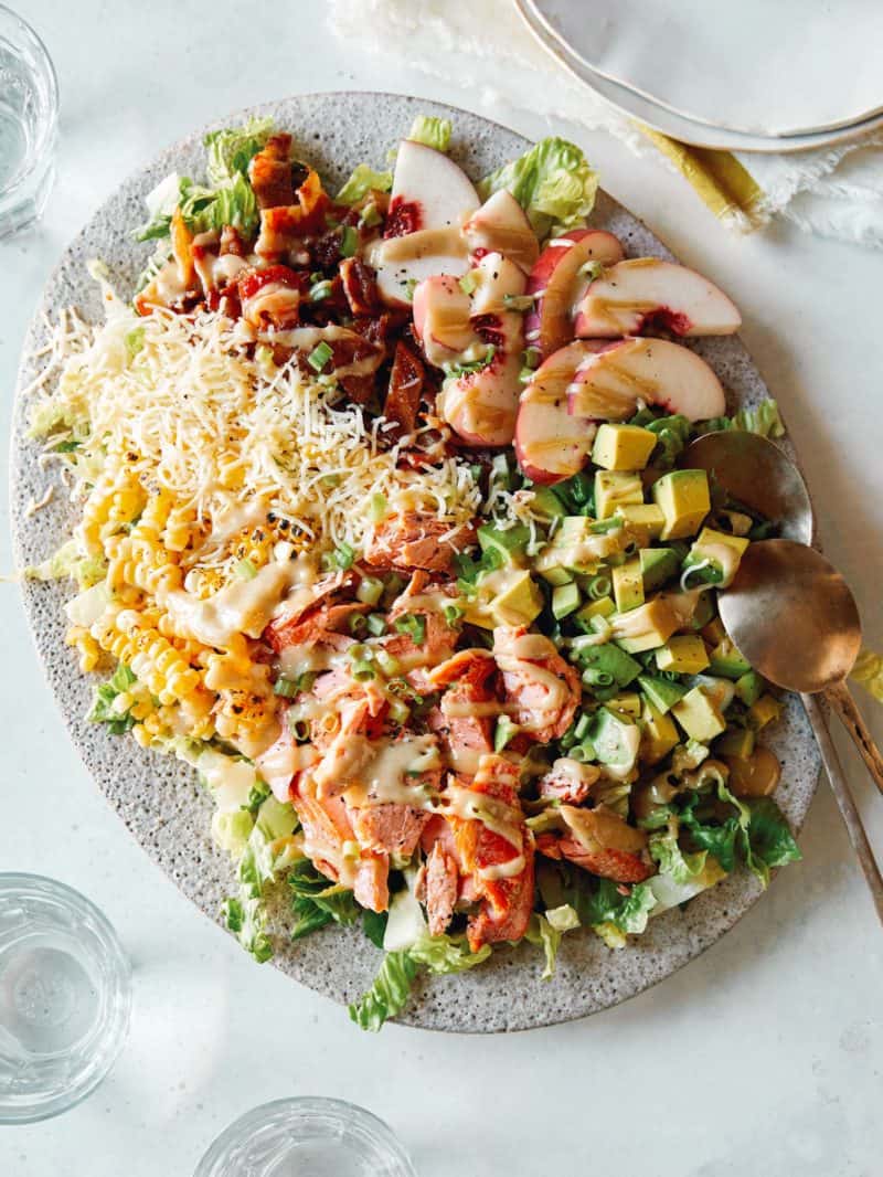 Salmon summer salad on a platter with a spoon. 